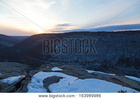 Quiet sunset at Blackwater Falls Park in winter West Virginia USA. Horizon over Appalachian Mountains and a road trace in canyon.