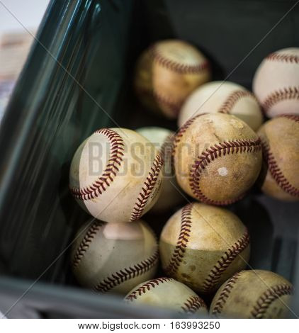 Several battered baseballs in a plastic box at flea market