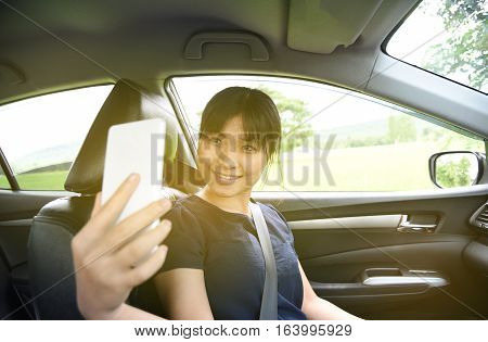 Woman taking a photo with smart phone in car with sunlight,Woman selfie in car