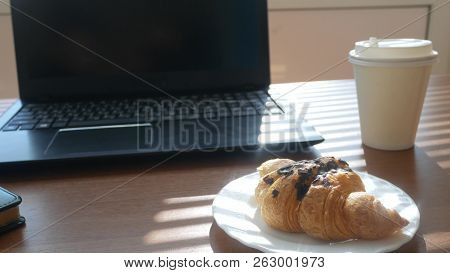 A Businessmans Desk With A Disposable Cup For Coffee And Fast Food. Open Laptop Computer. Breakfast 