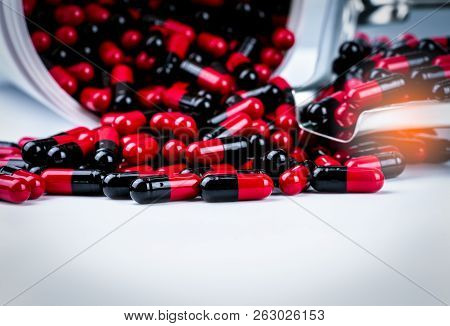 Red-black Antibiotic Capsule Pills Spill Out Of White Plastic Bottle Container And Drug Tray. Pharma