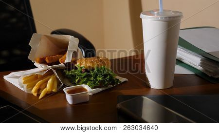 A Businessmans Table With A Disposable Cup For Coffee And Fast Food. Open A Laptop. Late Dinner At T
