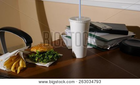 A Businessmans Table With A Disposable Cup For Coffee And Fast Food. Open A Laptop. Late Dinner At T