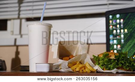 A Businessmans Table With A Disposable Cup For Coffee And Fast Food. Open A Laptop. Late Dinner At T