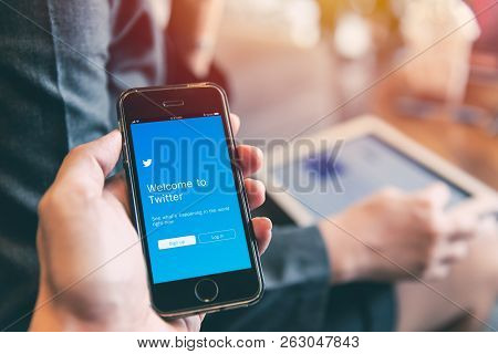 Twitter App On Iphone With People Using Tablet Background Closeup Male Hand Hold Social Network On S