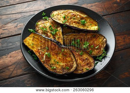 Healthy Vegeterain Oven Baked Aubergines, Eggplant With Parsley And Herbs In A Black Plate
