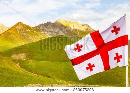 Beautiful View To Waving Flag Of Georgia On The Georgian Military Road Against The Background Of The