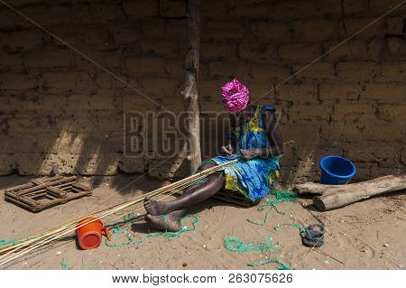 Orango Island, Guinea-bissau - February 3, 2018: An Old Woman Working In Front Of Her Hut At The Vil