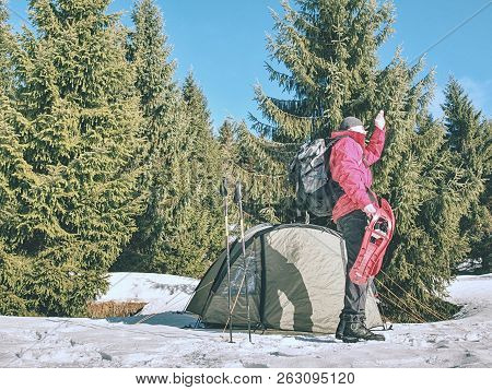 Hiker Prepare Equipment For Snowshoes Trip. Winter Few Days Trek In Snowy Mountains. Light Green Ten