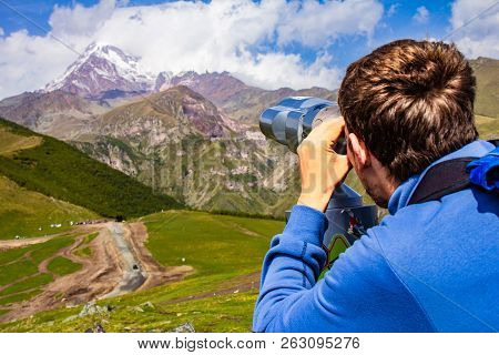 Man Looking In Binoscope Directed Towards The Snowy Mountain Tops Of Kazbeg From The View Point Gerg