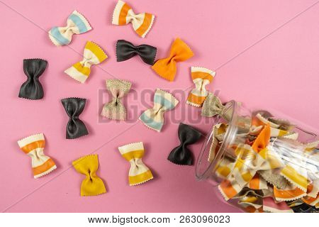 Colored Pasta In Glass Jar On Pink Background.
