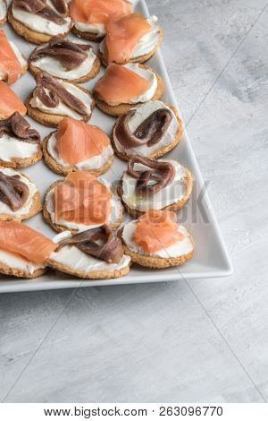 Homemade Canapes With Smoked Salmon, Anchovies And Cream Cheese. Lifht Gray Background. Copy Space.