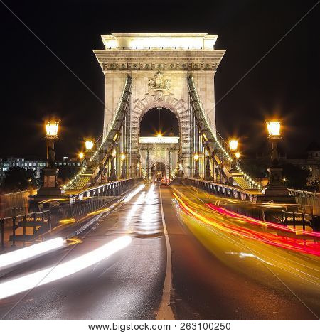 Traffic On Széchenyi Chain Bridge Over Danube River, Budapest City, Hungary. Night Scene
