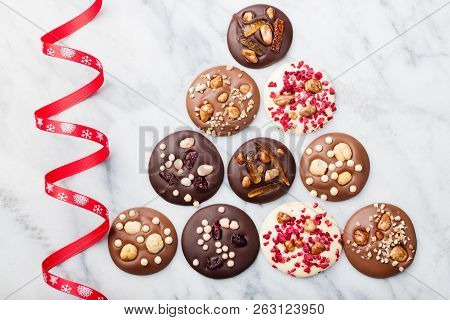 Chocolate Mediants, Bites, Candies, Cookies With Christmas Ribbon On Marble Table Background. Top Vi