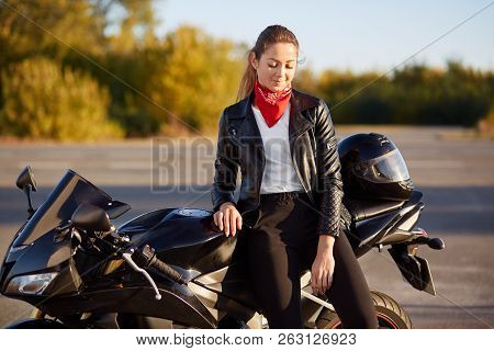 View Of Good Looking Young Woman Dressed In Black Jacket, Has Stylish Red Bandana On Neck, Dark Hair