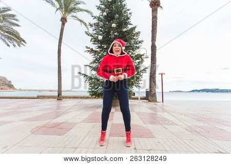 Christmas, Holidays And Humor Concept - Young Happy Woman Have Fun In Christmas Suit At Summer Near 