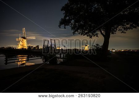 These Beautiful Windmills In Kinderdijk Are Illuminated With White Light At The Blue Hour