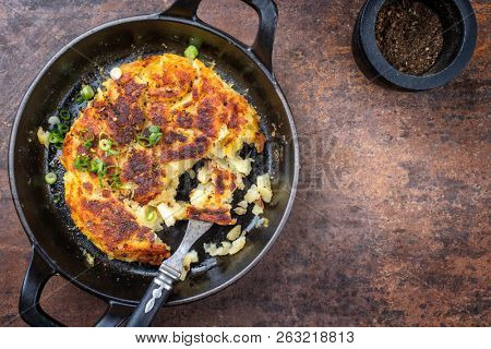 Traditional Swiss rosti as side dish with leek as top view in a frying pan with copy space right 