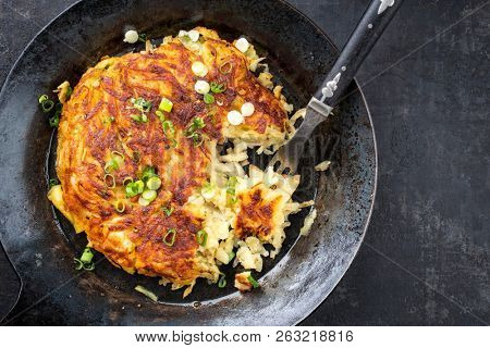 Traditional Swiss rosti as side dish with leek as top view in a frying pan with copy space right 