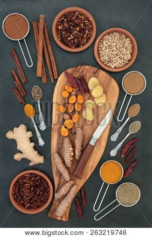 Spices for slimming and weight loss with fresh and dried turmeric, cumin, ginger, chilli, cinnamon and gymnema sylvestre used to suppress appetite. Top view on slate background.