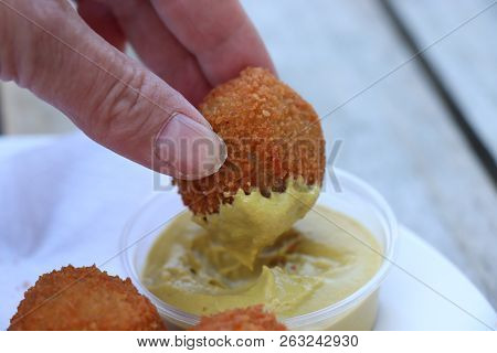 Dutch Snack:  Woman Eating A Bitterbal With Mustard. Warm Stuffed Fried Meatballs, Often Served With