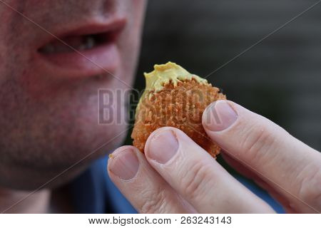 Dutch Snack:  Man Eating A Bitterbal With Mustard. Warm Stuffed Fried Meatballs, Often Served With A