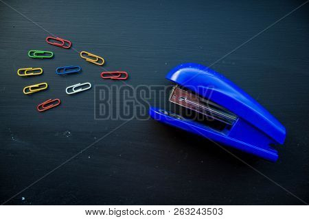 A Stepler And Colored Clips On Black Background