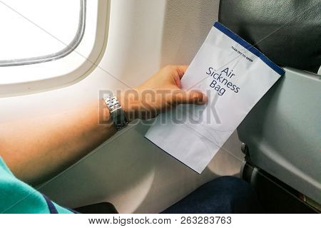 Passenger Holding Air Sickness Vomit Bag In Airplane
