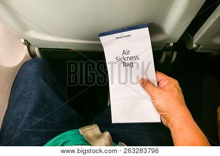 Passenger Holding Air Sickness Vomit Bag In Airplane