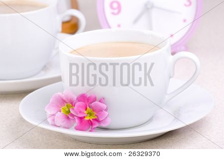 杯子装满了咖啡和时钟在背景中。