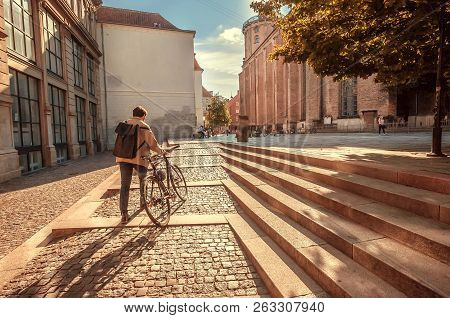 Copenhagen, Denmark - Sept 5: Outdoor Scene With Cyclist, His Bike And Old Church On Street Perspect