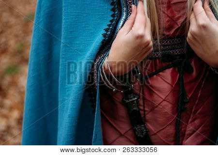 Celts. A Dagger Hangs On His Belt.girl With Long Hair, Blonde, Holding A Cape In Her Pink Dress