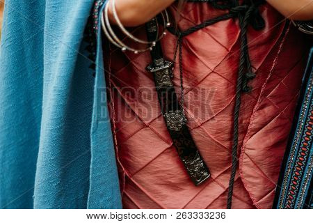 The Dagger In The Sheath Hangs On The Belt Of A Girl In A Pink Dress, With A Blue Cape.weapon, Self-