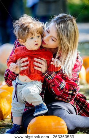 Young Mother With A Child On A Lawm With A Pumpkins. Autumn Season Time.
