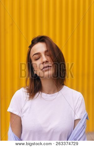 Portrait Attractive Woman On Yellow Background. She Look On Camera Pretentious Or Arrogantly.