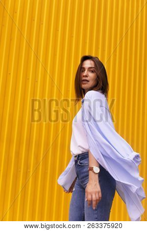 Portrait Attractive Woman On Yellow Background. She Look On Camera Pretentious Or Arrogantly.