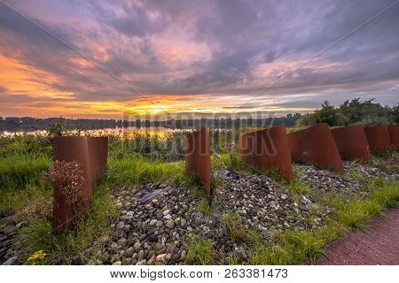 Curved Metal Objects In Landscape With Lake And Sunset At Piccardthofplas Groningen City, Netherland
