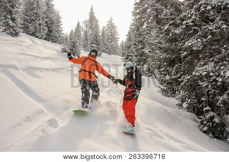 Two Snowboarders Running Down The Slope Holding Hands In The Popular Tourist Resort In Goderzi, Geor