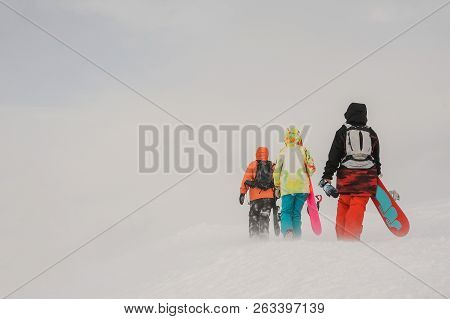 Three Snowboarders Walking With The Snowboard In The Mountain Down The Hill In The Popular Tourist R