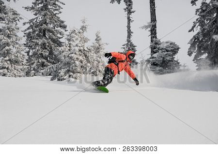 Man Fast Riding Down The Mountain Hill On The Snowboard On The Background Of Trees In The Mountain T