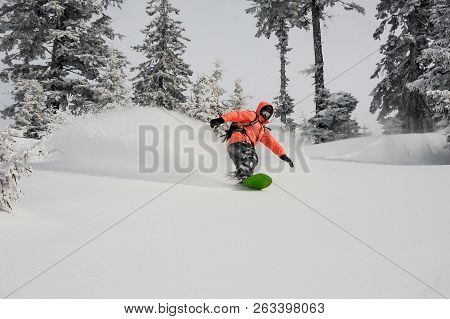 Man Running Down The Mountain Slope On The Snowboard On The Background Of Sky In The Mountain Touris