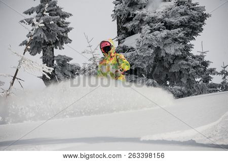Girl Running Down The Mountain Hill On The Snowboard On The Background Of Sky And Trees In The Mount
