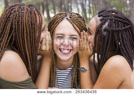 Three Young And Beautiful Girls, With Braided Hair, Laughing And Whispering Secrets