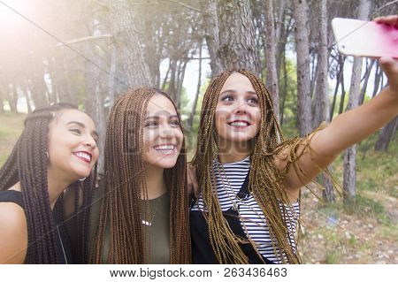 Three Young And Beautiful Girls, With Braided Hair, Taking Selfie