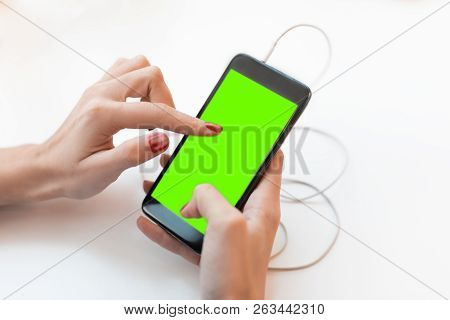 The Female Hand Caucasian Woman Holds Phone With The Thrust Wire From Earphones. On The Screen The H