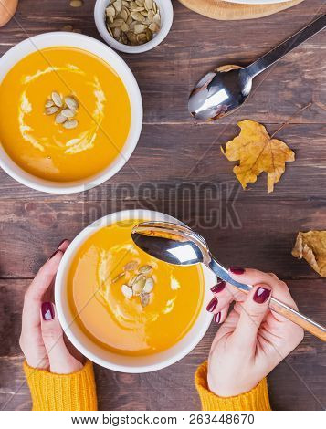 Womans Hands Holding Table Sppoon Near The Bowl Of Delecious Homemade Pumpkin Soup