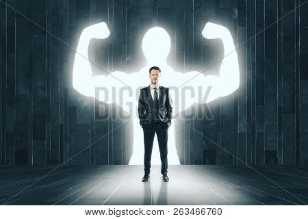 Businessman With Muscly Arms In Concrete Interior. Confidence And Power Concept
