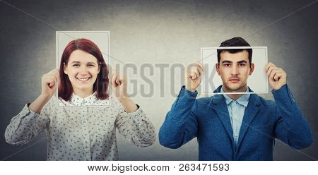 Businessman And Woman Covering Their Faces Using Photo Sheets With Happy And Sad Portrait Emoticon, 