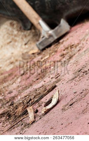 Piece Of Broken Wood Lying On The Ground With Splitting Axe Leaning On Tyre In Background
