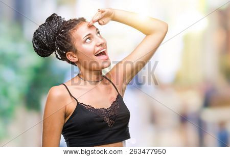 Young braided hair african american with pigmentation blemish birth mark over isolated background very happy and smiling looking far away with hand over head. Searching concept.